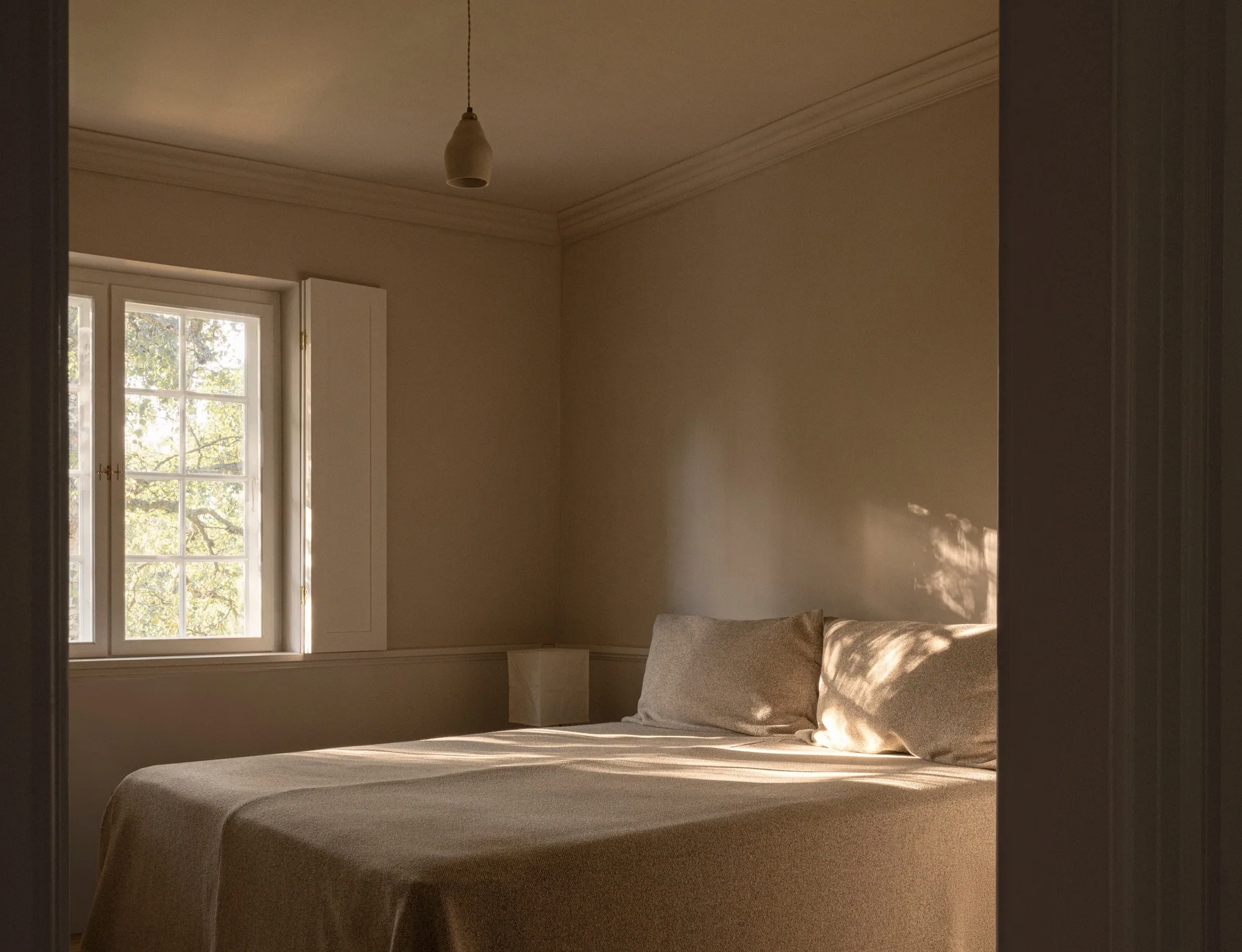 Sabah ışığı yatağa düşüyor; keten ve sakin duvarlar — NORM Architects, Guest House No. 16